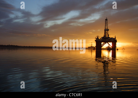 Olio della piattaforma di perforazione, con il sole che sorge dietro di esso, in Cromarty Firth, Scozia nel Regno Unito. Foto Stock