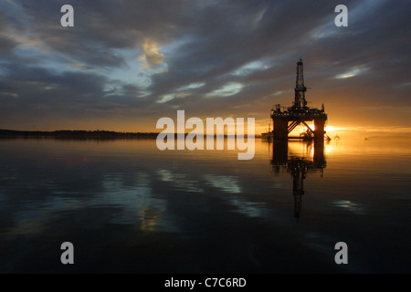 Olio della piattaforma di perforazione, con il sole che sorge dietro di esso, in Cromarty Firth, Scozia nel Regno Unito. Foto Stock