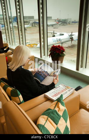 Regno Unito, Manchester Airport, passeggeri in attesa in Emirates Airlines Business Class Lounge con vista sul piazzale di sosta Foto Stock