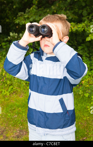 A sette anni di vecchio ragazzo birdwatching con il binocolo a Fairhaven bosco e acqua da giardino in Sud Walsham , Norfolk , Regno Unito Foto Stock