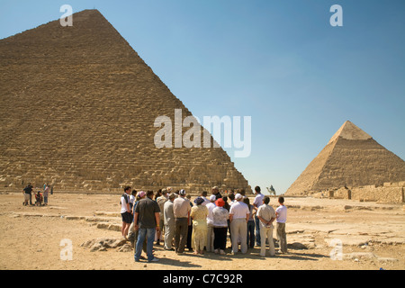 I turisti di fronte alla grande Piramide di Khufu con la piramide di Khafre nella distanza sull'Altopiano di Giza a Il Cairo, Egitto Foto Stock