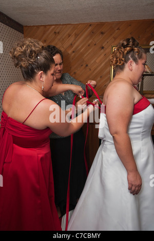 Damigella d'onore e la madre aiutano la sposa con il vestito immagini foto verticali in alta risoluzione USA Foto Stock