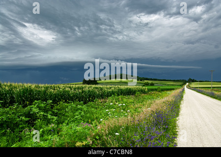 Nuvole temporalesche su una strada di campagna Foto Stock