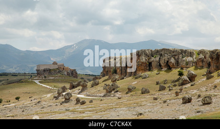 Lava vulcanica del terreno di cenere con la vecchia chiesa su di una collina e gamma mounatin in background Cappadocia , tracce di sporco, cloudscape Foto Stock