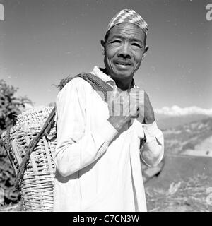 Ritratto di Nepalise locale uomo cestello di trasporto su strada vicino a Seti River Valley in Nepal. Prese negli anni cinquanta da J. Allan contanti. Foto Stock
