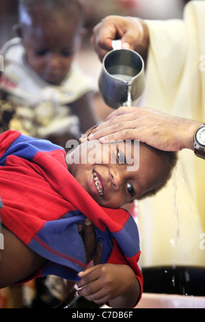 Il bambino nelle braccia della madre è battezzato (battezzata, chiamato da un prete cattolico. Kiunga, Papua Nuova Guinea Foto Stock