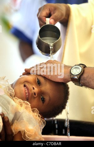 Il bambino nelle braccia della madre è battezzato (battezzata, chiamato da un prete cattolico. Kiunga, Papua Nuova Guinea Foto Stock