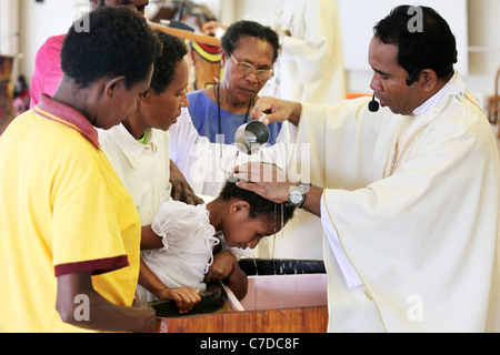 Il bambino nelle braccia della madre è battezzato (battezzata, chiamato da un prete cattolico. Kiunga, Papua Nuova Guinea Foto Stock