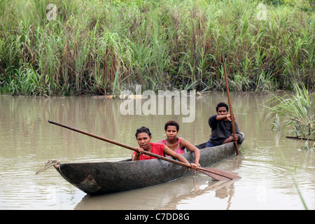 Tre ragazze in una piroga sulle rive di un fiume in Papua Nuova Guinea Foto Stock