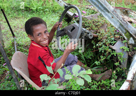 Ragazzo in un abbandonato ricoperta di rusty auto rottamata, Papua Nuova Guinea Foto Stock