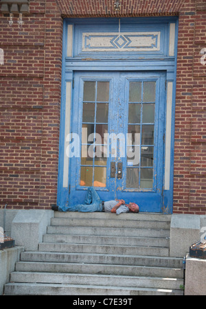 Un uomo addormentato sui gradini di un edificio su Thames Street in Fells Point, Baltimore, Maryland USA Foto Stock