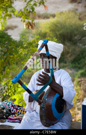 Uomo a corde suonare uno strumento musicale presso il Tempio di Philae, Egitto Foto Stock