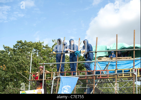 Dale Farm lo sfratto. Tre manifestanti mascherati in piedi sulla piattaforma sopra l'ingresso principale a guardare per avvicinarsi a ufficiali giudiziari. Foto Stock