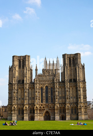 Cattedrale di Wells con un cielo blu in formato verticale con la gente sul prato Foto Stock