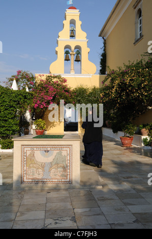 Greco Ortodosso di Monaco a piedi attraverso il cortile del monastero della Vergine Maria Paleokastritsa Corfu Grecia Foto Stock