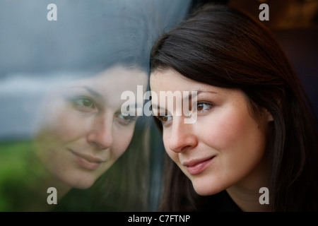 Giovane donna guardando fuori da una finestra su un viaggio in treno Foto Stock