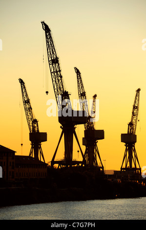 Gru di un cantiere navale di Glasgow stagliano contro il cielo di alba/tramonto (potrebbe essere sia). Spazio per il testo nel cielo. Foto Stock