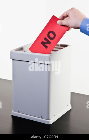 Un uomo mettendo un ballottaggio con la parola NO scritto su di esso in un urna, close-up le mani Foto Stock