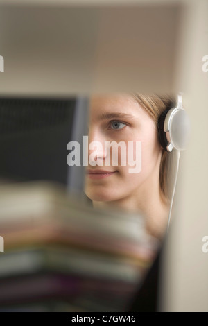 Una giovane donna che indossa le cuffie oscurati da oggetti sfocata Foto Stock