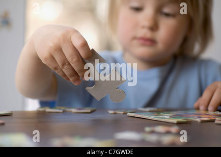 Un giovane ragazzo in possesso di un pezzo di puzzle Foto Stock