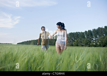 Una donna tirando il suo fidanzato attraverso un campo Foto Stock