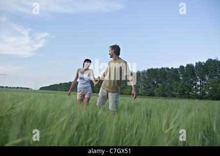 Un uomo tirando la sua ragazza attraverso un campo Foto Stock