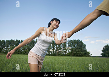 Un uomo tirando la sua ragazza attraverso un campo Foto Stock