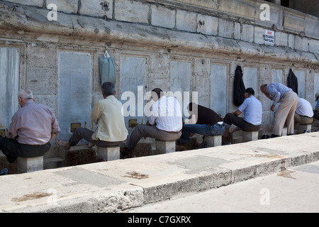 Uomini musulmani lavare i piedi prima di pregare nella nuova moschea, Istanbul, Turchia Foto Stock