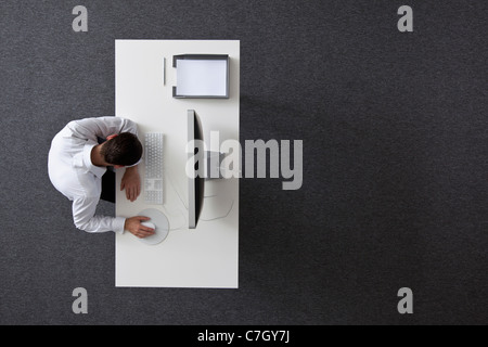 Un imprenditore con la sua testa in appoggio sul suo braccio seduti ad una scrivania, vista aerea Foto Stock