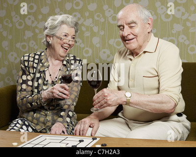 Coppia senior di bere vino rosso fare un brindisi sul lettino Foto Stock
