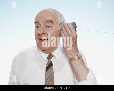 Senior uomo in ascolto sulla lattina può telefono Foto Stock