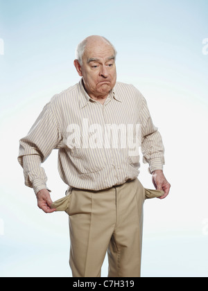 Senior l uomo trasforma le sue tasche interne a simboleggiare non avente alcun denaro Foto Stock