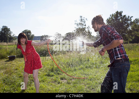 L uomo e la donna spray ogni altro con acqua nel campo Foto Stock