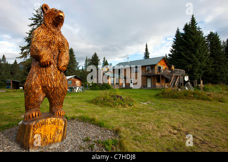 Vista del salmone argento Creek Lodge di legno di orso grizzly statua, il Parco Nazionale del Lago Clark, Alaska, Stati Uniti d'America Foto Stock