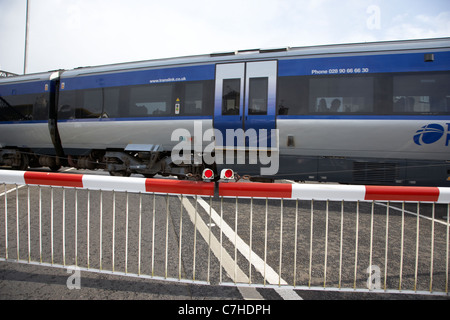 Treno nir livello passando attraversando le barriere verso il basso chiuso castlerock stazione ferroviaria Irlanda del nord italia azione sfocatura del movimento Foto Stock