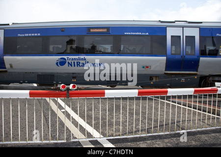 Treno nir livello passando attraversando le barriere verso il basso chiuso castlerock stazione ferroviaria Irlanda del nord italia azione sfocatura del movimento Foto Stock