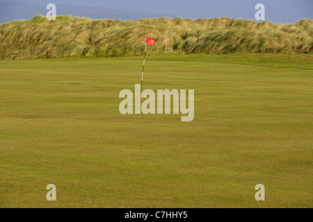 Foro e bandiera sul palo verde su un irlandese del campo da golf links Foto Stock