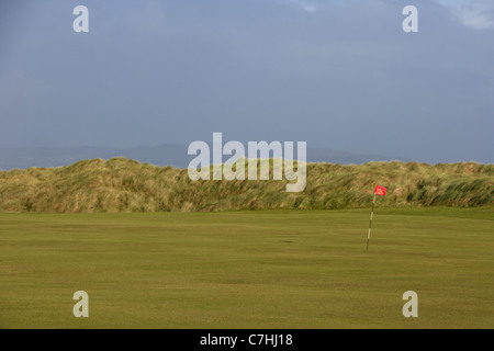 Foro e bandiera sul palo verde su un irlandese del campo da golf links Foto Stock