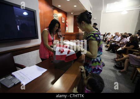 Giovane donna firma di documenti che accetta la cittadinanza canadese in una cerimonia di cittadinanza di Kitchener, Ontario Foto Stock