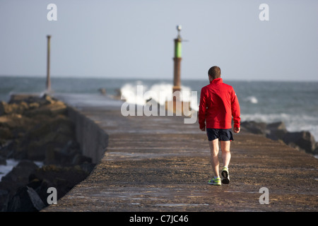 Uomo che cammina lungo il molo bann bocca nella contea di derry Londonderry Irlanda del Nord Foto Stock