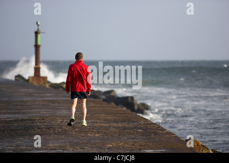 Uomo che cammina lungo il molo bann bocca nella contea di derry Londonderry Irlanda del Nord Foto Stock