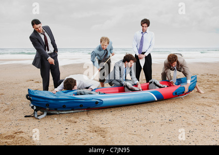 Imprenditori con canoe sulla spiaggia Foto Stock