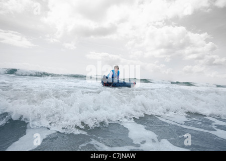 Imprenditore spingendo la canoa in ocean Foto Stock