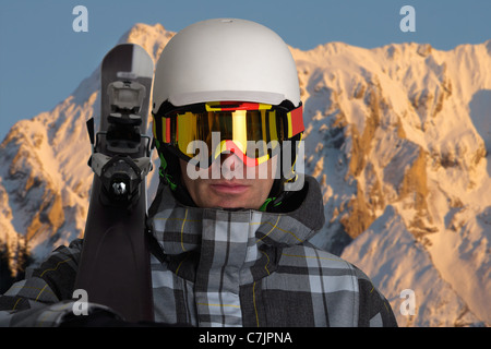 L'uomo portare sci nelle montagne innevate Foto Stock