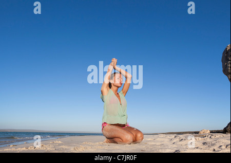 Donna in bikini Inginocchiati sulla spiaggia Foto Stock