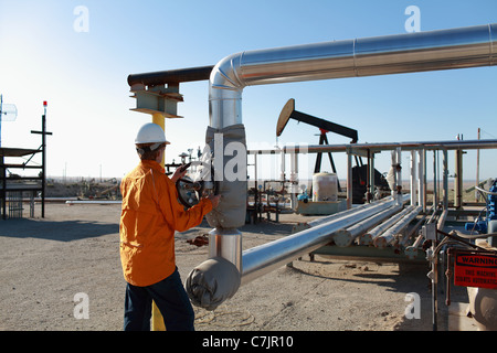 Lavoratore tubazioni di regolazione al campo dell'olio Foto Stock