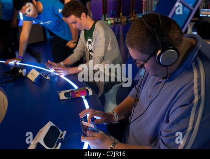 I giovani che cercano più recenti Sony PS e console di giochi a una fiera a Londra, Regno Unito Foto Stock