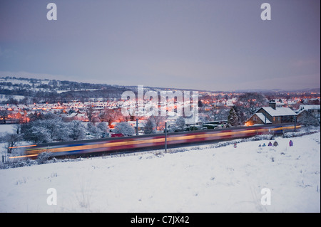 Un treno che corre lungo la linea di Wharfedale in un giorno di neve. Foto Stock