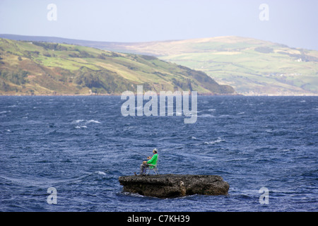 Un manichino vestito come un pescatore sorge su un promontorio roccioso nel mare d' Irlanda nei pressi del villaggio di Waterfoot, sulla contea di Antrim Foto Stock