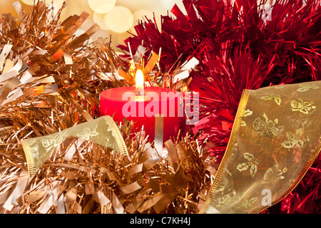 Christmas Candle burning circondato da golden, rosso e nastro verde Foto Stock